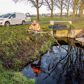 Bij de stuw aan de Lupineweg verwijdert Boom ook meteen een flinke tak die overdwars in de waterloop de doorgang verspert.