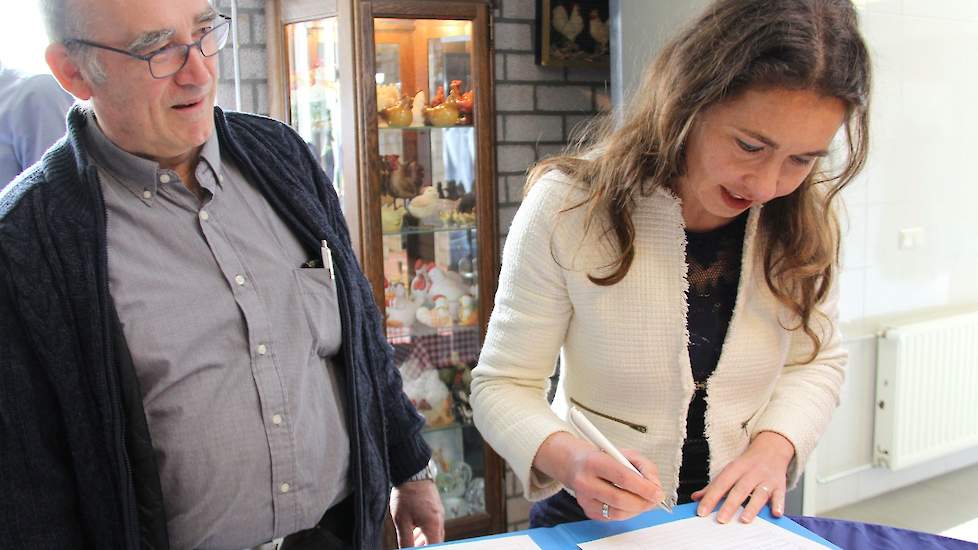 Toon van de Laar is maar wat graag getuige van het zetten van de handtekening door Spierings, in het gastenboek op het bedrijf.