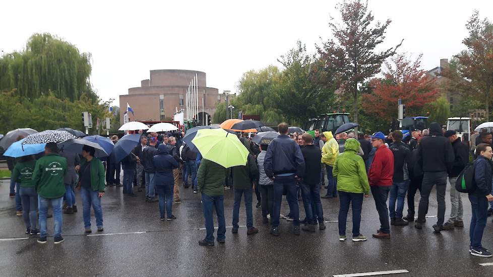 Boeren staan in de regen te wachten totdat zij naar binnen kunnen.