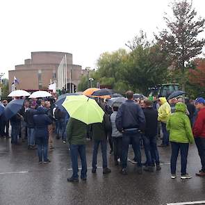 Boeren staan in de regen te wachten totdat zij naar binnen kunnen.